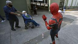 Seseorang yang mengenakan kostum Spiderman menyapa seorang wanita di atas kursi roda setelah disuntik vaksin covid-19 Pfizer-BioNTech di Mexico City, Meksiko, Selasa (28/12/2021). Spiderman tersebut dipekerjakan oleh Pemerintah Kota untuk menghibur para peserta vaksinasi. (ALFREDO ESTRELLA / AFP)