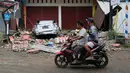 Pengendara motor melihat sebuah mobil yang hancur akibat gempa bumi di Mamuju, Sulawesi Barat,  Jumat (15/1/2021). Jaringan listrik di wilayah itu juga dilaporkan mengalami pemadaman. (AP Photo/Sadly Ashari Said)