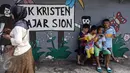 Seorang ibu yang sedang melintas dan anak-anak tengah duduk di taman bermain TK Kristen Fajar Sion, Jakarta Barat, Minggu (8/1). Guna mengurangi trauma kebakaran, mereka memanfaatkan taman bermain di sekolah tersebut. (Liputan6.com/Fery Pradolo)