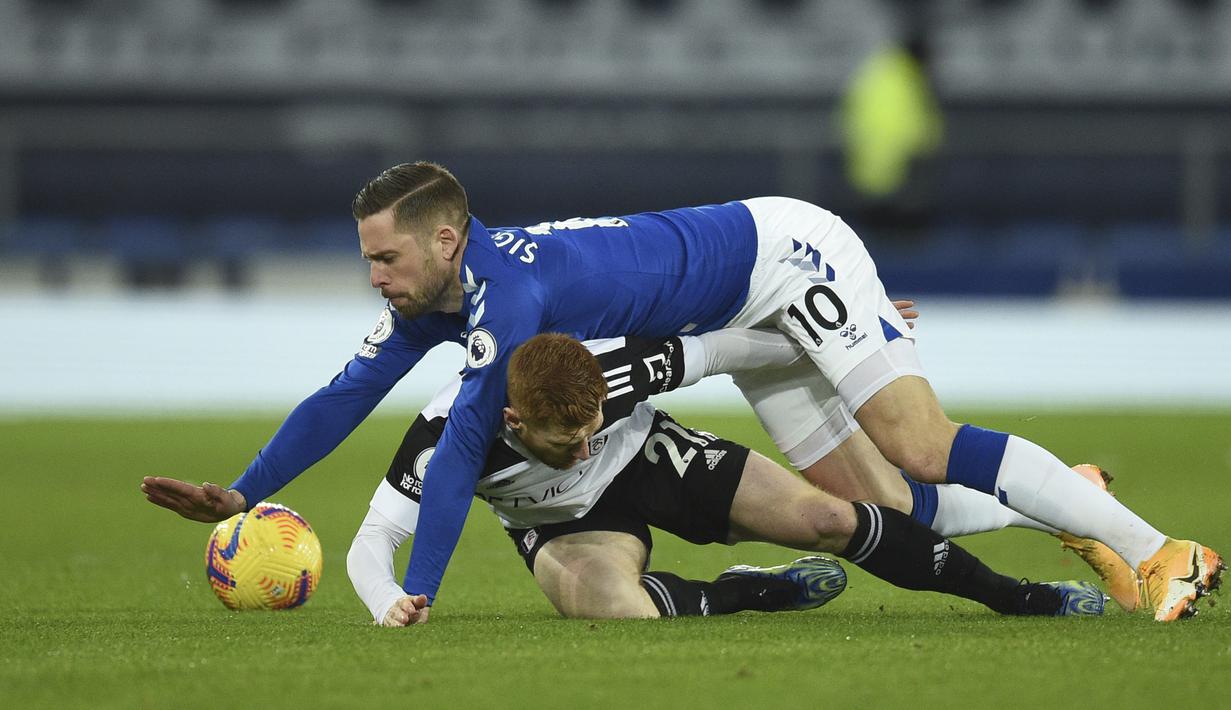 Gelandang Everton, Gylfi Sigurdsson (atas) dan gelandang Fulham, Harrison Reed berduel memperebutkan bola dalam laga lanjutan Liga Inggris 2020/21 pekan ke-24 di Goodison Park, Liverpool, Minggu (14/2/2021). Everton kalah 0-2 dari Fulham. (AP/Oli Scarff/Pool)