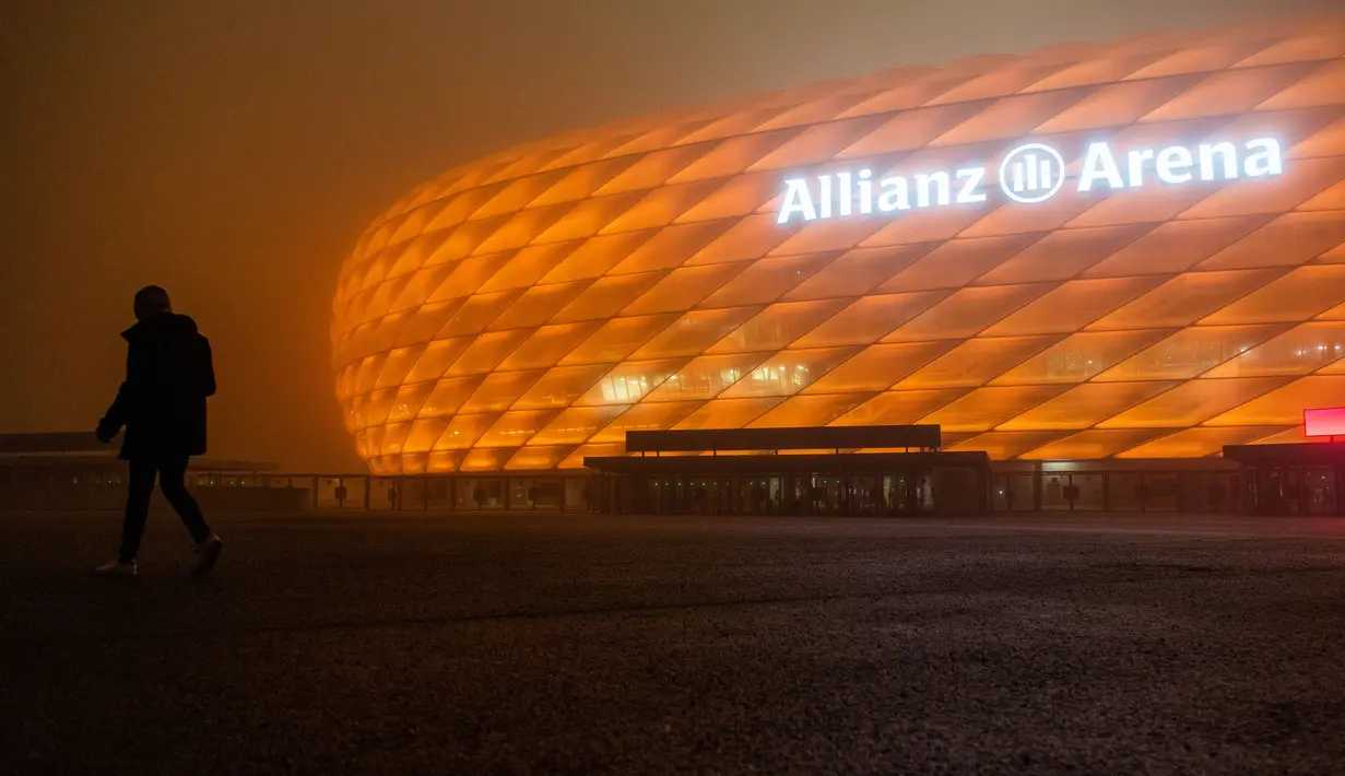 Allianz Arena, markas dari FC Bayern Munchen, diterangi warna oranye untuk kampanye "Orange the World" di Munich, Jerman, Senin (25/11/2019). Cahaya berwarna oranye untuk melambangkan partisipasi mendukung penghapusan kekerasan terhadap perempuan. (Lino Mirgeler/dpa/AFP)