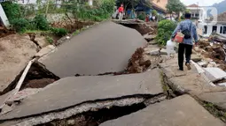 Warga melintas di jalan yang rusak parah pascagempa bumi magnitudo 5,6 di Kampung Cisarua, Desa Sarampad, Kabupaten Cianjur, Jawa Barat, Rabu (23/11/2022). Kepala BNPB Letjen TNI Suharyanto mengonfirmasi korban meninggal akibat gempa Kabupaten Cianjur, Jawa Barat, berjumlah 268 orang. (merdeka.com/Arie Basuki)