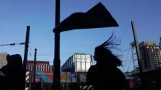 Orang-orang berjalan melewati poster yang tertiup angin, di sebuah jalan di London, Senin, 22 Januari 2024. (AP Photo/Kin Cheung)
