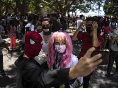 Penggemar anime dan video game Kuba berpakaian seperti pahlawan atau karakter favorit mereka, berpose untuk selfie selama parade Cosplay di sela-sela Pameran Buku Internasional Havana, di Havana, Sabtu (23/4/2022). (AP Photo/ Ramon Espinosa)