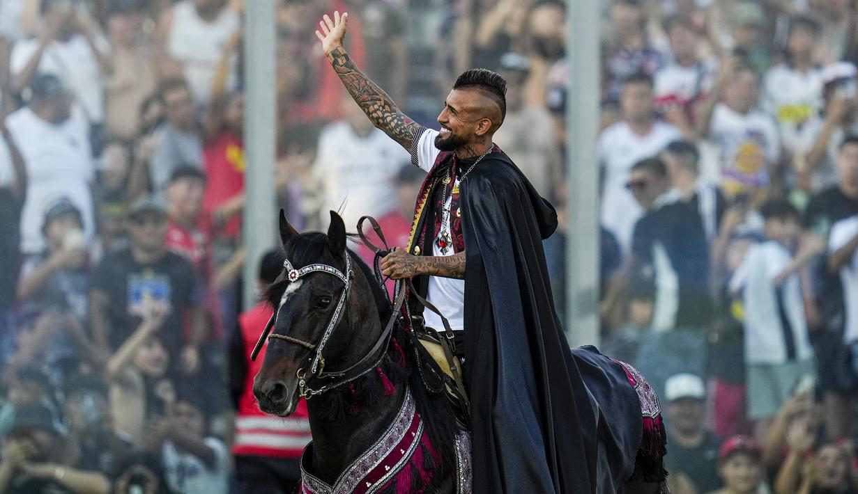 Arturo Vidal melambaikan tangan kepada para fans di atas kuda saat acara perkenalan pemain baru klub Liga Chile, Colo-Colo di Stadion Monumental David Arellano, Chili, Jumat (2/2/2024) WIB. (AP Photo/Esteban Felix)