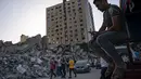 Orang-orang berkumpul untuk melihat puing-puing gedung al-Jalaa menyusul gencatan senjata yang dicapai setelah perang 11 hari antara Hamas dan Israel, di Kota Gaza, Jumat (21/5/2021). Bangunan itu menampung biro Associated Press di Kota Gaza selama 15 tahun. (AP Photo/John Minchillo)