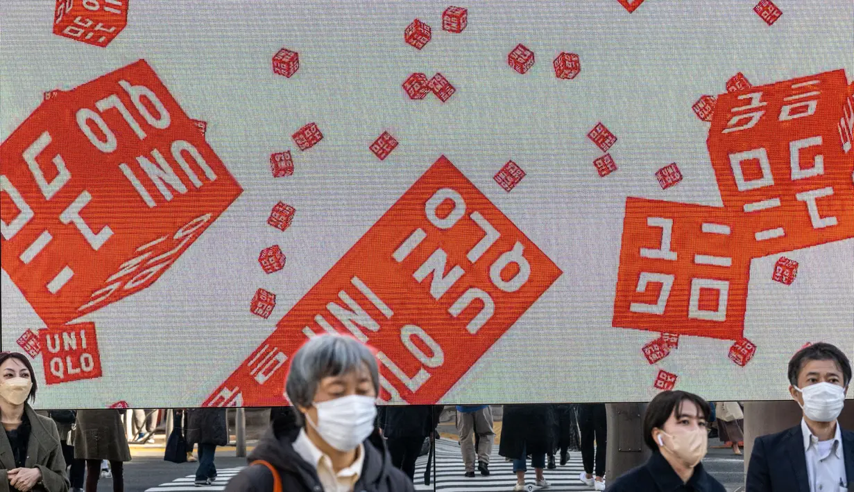 Pejalan kaki berjalan di depan toko Uniqlo yang dioperasikan oleh Fast Retailing Jepang di Tokyo, Rabu (11/1/2023). Fast Retailing, yang mengoperasikan lebih dari 3.500 toko pakaian di seluruh dunia, mengatakan sistem remunerasinya akan direvisi mulai Maret, dan level di Jepang akan dinaikkan secara signifikan. (Philip FONG / AFP)