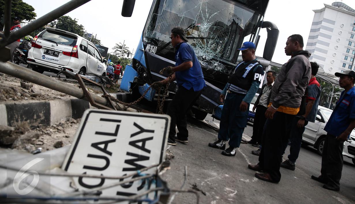 Petugas mengevakuasi bus gandeng TransJakarta yang menabrak pagar pembatas jalan, di Jalan Gunung Sahari, Jakarta, Selasa (6/9). Tak ada korban jiwa dalam insiden yang diduga lantaran sopir mengantuk tersebut. (Liputan6.com/Faizal Fanani)