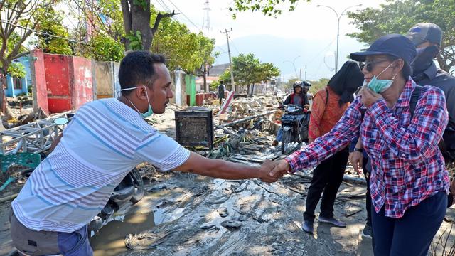 Menteri Kelautan dan Perikanan Susi Pudjiastuti bersalaman dengan salah seorang warga di sekitar lokasi rerutuhan bangunan. (Istimewa)