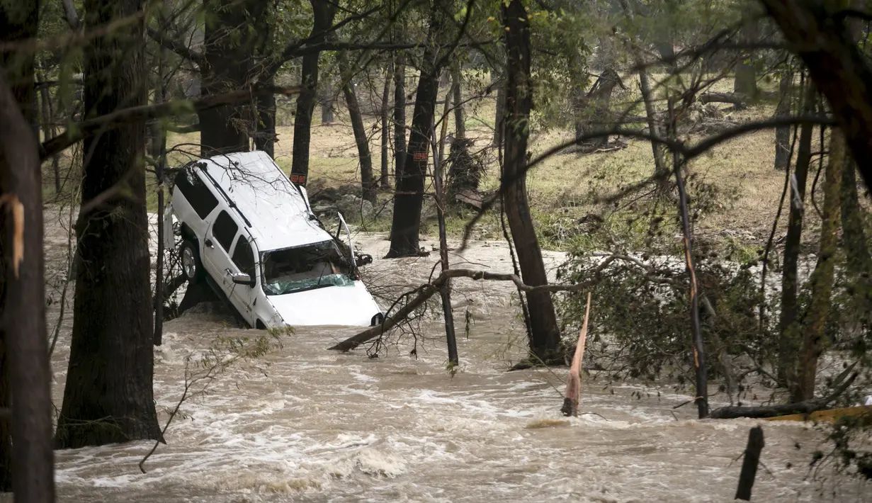 Mobil terjebak disebuah pohon dengan luapan air sungai yang deras akibat Tornado yang menyaou bagian kota Texas, Amerika Serikat, Jumat (30/10/2015). Tornando disertai hujan ini mengakibatkan  Jalanan menjadi banjir. (REUTERS/Ilana Panich - Linsman)