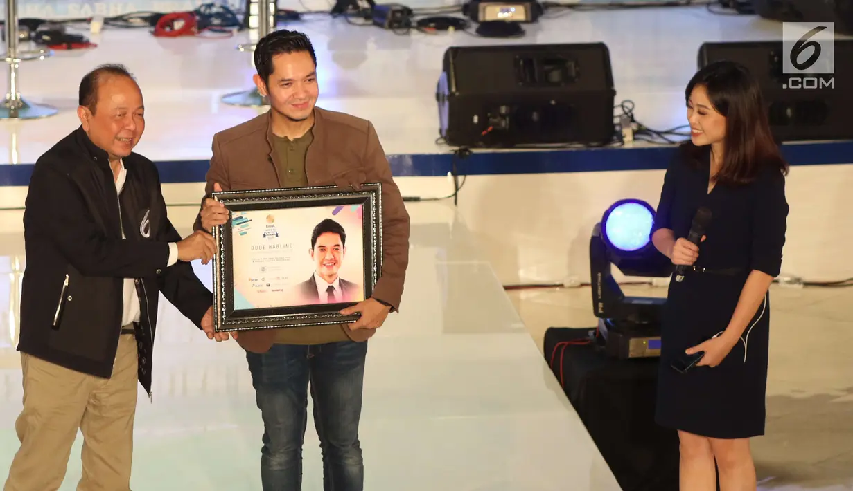 Pemimpin Redaksi SCTV, Indosiar, dan Liputan6.com Mohamad Teguh memberikan cinderamata kepada Dude Harlino usai menjadi pembicara pada acara EGTC 2017 di Graha Sabha Pramana Universitas Gadjah Mada, Yogyakarta, Selasa (31/10). (Liputan6.com/Helmi Afandi)