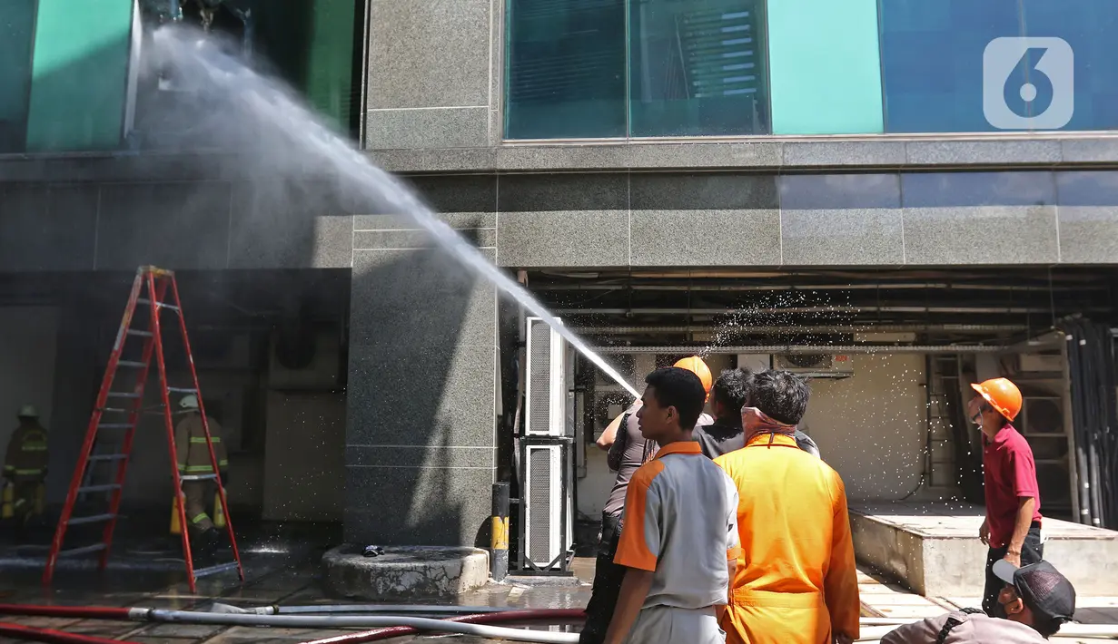 Petugas menyemprotkan air saat berusaha memadamkan kebakaran di Gedung Cyber 1, Jakarta, Kamis (2/12/2021). Sampai saat ini, penyebab kebakaran masih belum diketahui. (Liputan6.com/Herman Zakharia)