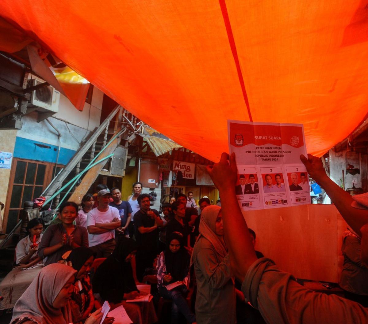 Warga menyaksikan  penghitungan suara Pemilu 2024 yang berlangsung di TPS 56, Kebun Melati, Tanah Abang, Rabu (14/02/2024).  Penghitungan suara di kawasan ini didominasi para pemilih 01. Foto: merdeka.com / arie basuki<br>