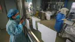 Petugas medis berbicara dengan koleganya yang bekerja di bangsal isolasi Rumah Sakit Jinyintan, Wuhan, Provinsi Hubei, China, Kamis (13/2/2020). Data terbaru tanggal 14 Februari 2020 menunjukkan jumlah korban tewas akibat virus corona mendekati angka 1.500. (Chinatopix Via AP)