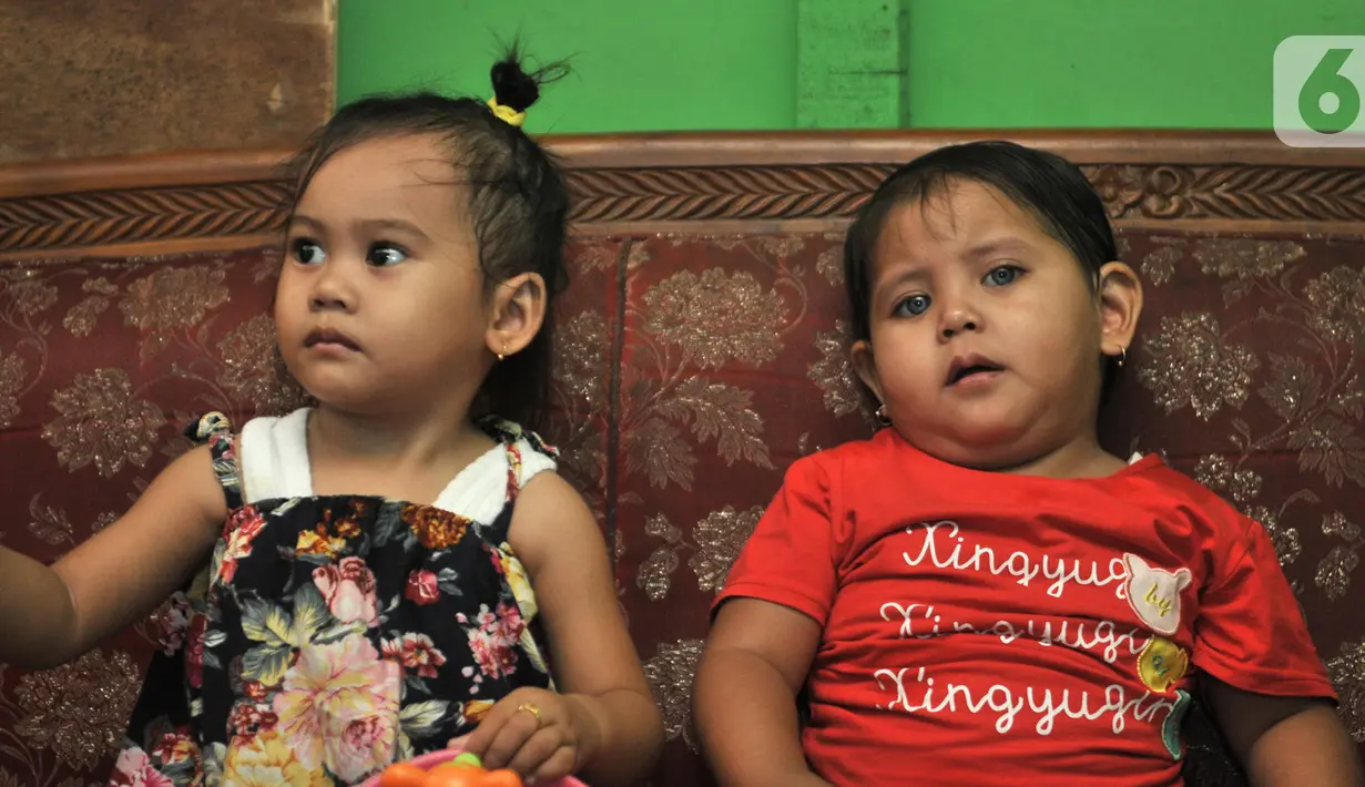 Fauziah Afiqa (kanan) saat bermain dengan balita lainnya di kediamannya di Kampung Bulak Sentul, Harapan Jaya, Bekasi, Jawa Barat, Kamis (10/10/2019). Keluarga beberapa kali membawa Afiqa ke dokter spesialis untuk memeriksa matanya namun hasilnya normal. (merdeka.com/Iqbal Nugroho)