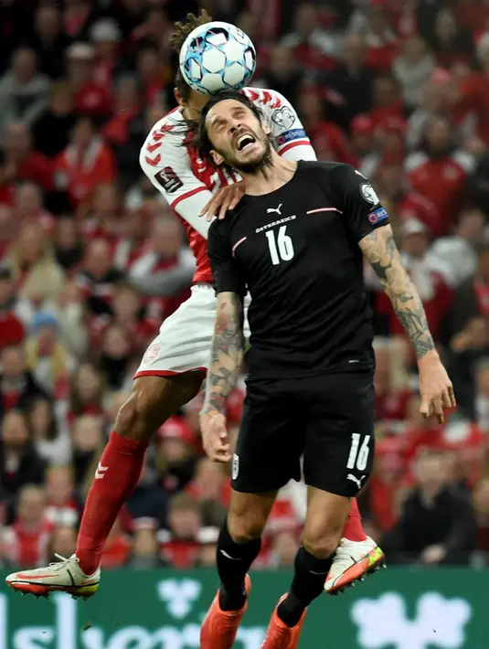 Pemain Denmark Yussuf Poulsen (kiri) memperebutkan bola dengan pemain Austria Christopher Trimmel (kanan) pada pertandingan Grup F kualifikasi Piala Dunia 2022 di Kopenhagen, Denmark, Selasa (12/10/2021). Denmark menang 1-0. (ROBERT JAEGER/APA/AFP)