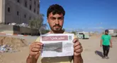 Seorang pria Palestina menunjukkan salah satu selebaran yang disebarkan oleh tentara Israel di Beit Hanun, Jalur Gaza utara pada 19 Maret 2025. (BASHAR TALEB/AFP)
