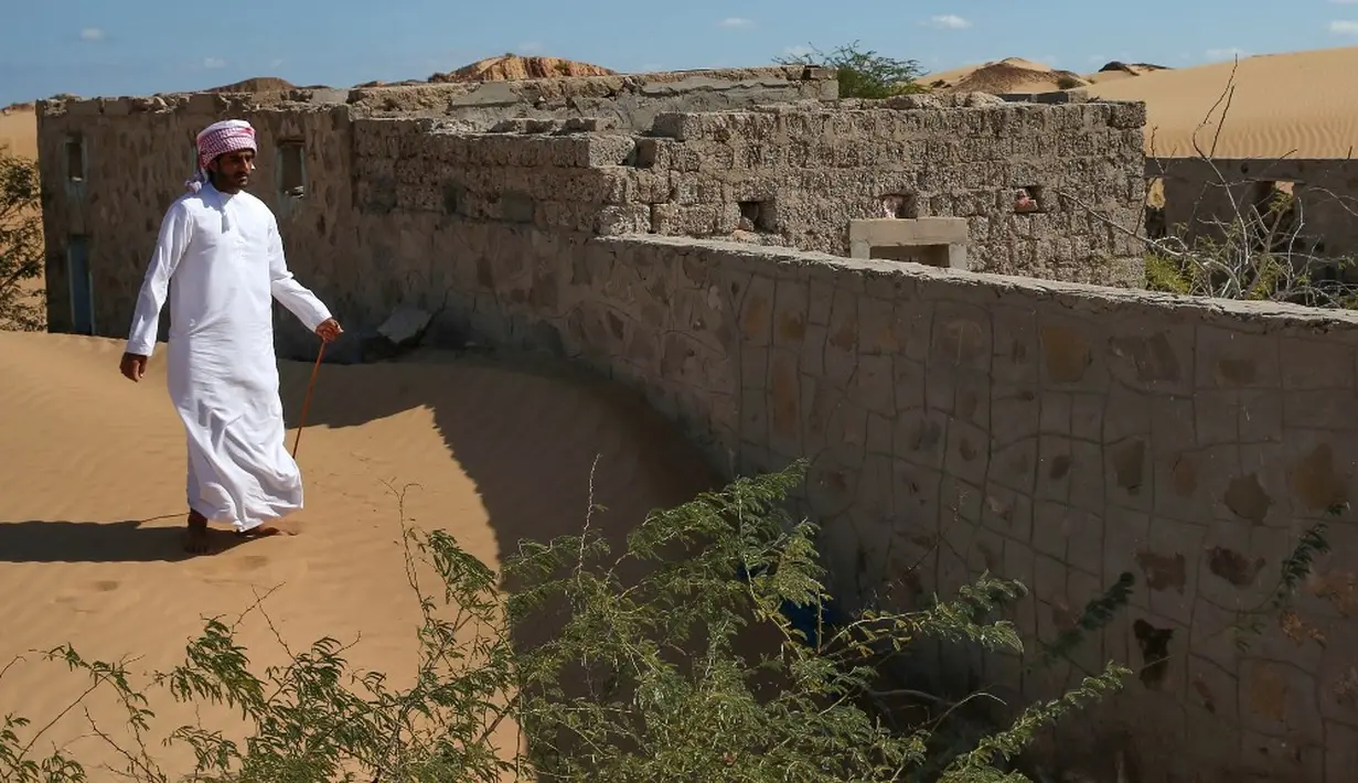 Seorang mantan penduduk Wadi al-Murr berjalan dekat sebuah rumah terlantar di Desa Omani, Wadi al-Murr, Oman, 31 Desember 2020. Gurun pasir meluas ke seluruh dunia, didorong oleh perubahan iklim, dan populasi yang terdampak hanya memiliki sedikit "senjata" untuk melawannya. (MOHAMMED MAHJOUB/AFP)