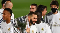 Striker Real Madrid, Karim Benzema, mengangkat trofi juara La Liga usai mengalahkan Villrreal pada laga lanjutan pekan ke-37 di Estadio Alfredo Di Stefano, Jumat (17/7/2020) dini hari WIB. Real Madrid menang 2-1 atas Villarreal. (AFP/Gabriel Bouys)