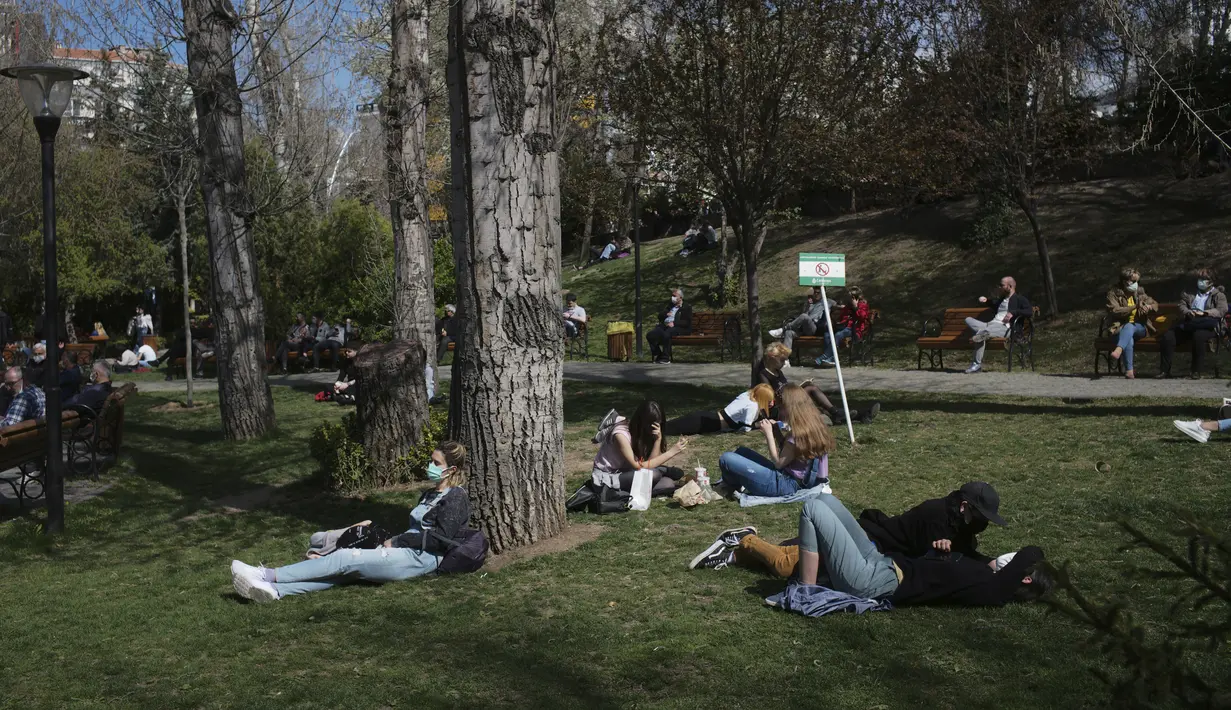 Orang-orang duduk di taman beberapa jam sebelum penguncian nasional, di Ankara, Turki, Rabu (21/4/2021). Turki, yang sekarang berada di antara negara-negara yang paling parah terkena dampak, juga melaporkan 61.967 kasus baru Corona yang dikonfirmasi. (AP/Burhan Ozbilici)