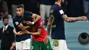 Penyerang Prancis #10 Kylian Mbappe menghibur bek Maroko #02 Achraf Hakimi pada akhir babak semifinal Piala Dunia 2022 di Al Bayt Stadium, Kamis (15/12/2022) dini hari WIB. Warganet di media sosial ramai mengomentari momen bromance Mbappe dan Hakimi ini. (Photo by GABRIEL BOUYS / AFP)