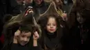 Sofia, 6 tahun, tengah, anggota kelompok beruang tradisional mengambil bagian dalam parade sebelum tampil di festival di Moinesti, Rumania utara, Rabu, 27 Desember 2023. (AP Photo/Vadim Ghirda)