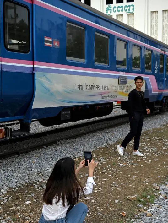 Foto yang diambil pada 5 Juni 2021 menunjukkan seorang pria berpose di samping kereta api di stasiun kereta api di Phnom Penh. Gerbong kereta diubah menjadi kafe setelah selama pandemi corona sebagian besar perjalanan kereta api di Kamboja dihentikan. (TANG CHHIN Sothy/AFP)