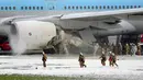 Petugas pemadam kebakaran menyemprotkan busa pada mesin pesawat Korean Air Lines di bandara Haneda di Tokyo, Jepang, (27/5). Insiden ini mendorong pemerintah untuk menutup sementara turun hub penerbangan tersibuk di Jepang. (Reuters/ Kyodo)