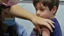 Bocah Israel, Itamar (5) disuntik dosis vaksin Covid-19 Pfizer/BioNTech Covid-19 di Meuhedet Healthcare Services Organization di Tel Aviv, saat Israel memulai kampanye vaksinasi virus corona untuk anak berusia 5 hingga 11 tahun, Senin (22/11/2021). (JACK GUEZ / AFP)