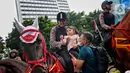 Polisi dari Detasemen Turangga Direktorat Polisi Satwa Polri menaiki seorang anak ke atas kuda saat Car Free Day (CFD) atau Hari Bebas Kendaraan Bermotor di kawasan Bundaran HI, Jakarta, Minggu (19/2/2023).Polisi berkuda selain ditugaskan untuk pengamanan simpatik juga untuk menghibur warga dan anak-anak saat Hari Bebas Kendaraan Bermotor serta memperkenalkan profesi tersebut kepada warga. (Lipitan6.com/Angga Yuniar)