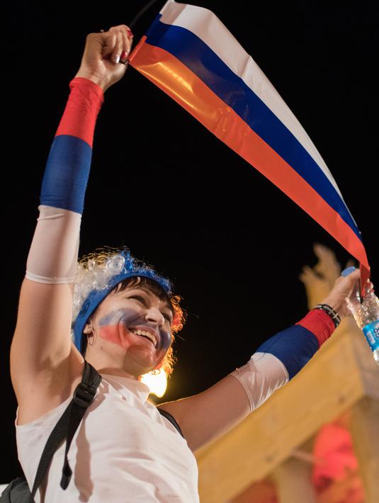 Suporter timnas Rusia merayakan kemenangan atas Mesir pada putaran kedua pertandingan grup A Piala Dunia di Volgograd, Rabu (20/6). Tuan rumah Piala Dunia, Rusia menang 3-1 dan kian berpeluang lolos ke 16 besar. (AFP PHOTO / NICOLAS ASFOURI)