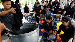 Relawan mewarnai pakaian pelayat agar menjadi hitam untuk dikenakan selama masa berkabung atas wafatnya raja Thailand Bhumibol Adulyadej di Grand Palace di Bangkok, Thailand (17/10). Relawan ini mewarnai pakaian warga secara suka rela.(Reuters/Edgar Su)