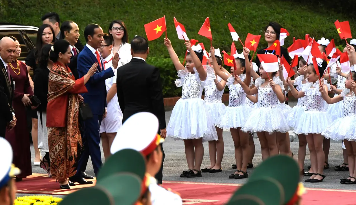 Presiden Jokowi dan Ibu Negara Iriana disambut puluhan anak berbaju balerina yang melambaikan bendera Vietnam dan Merah Putih, setibanya di Istana Kepresidenan, Hanoi, Vietnam, (11/9). (Nhac Nguyen/Pool photo via AP)