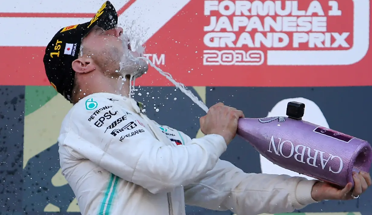Pembalap Mercedes, Valtteri Bottas menuangkan sampanye untuk dirinya sendiri di atas podium setelah menjuarai balapan Formula 1 (F1) GP Jepang di Sirkuit Suzuka, Minggu (13/10/2019). Bottas menjadi pembalap pertama yang menyentuh garis finis usai melakoni lomba 53 putaran. (AP/Toru Takahashi)