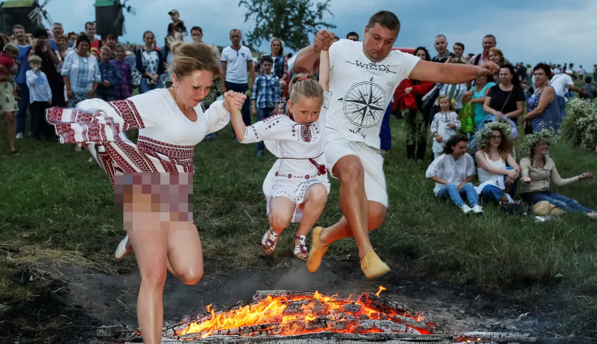 Warga melompati api unggun saat perayaan tradisional Ivan Kupala di Kiev, Ukraina, Rabu (6/7). Ivan's day merupakan tradisi pagan kuno sebagai ritual kesuburan di musim panas yang masih ada di Rusia dan Ukraina. (REUTERS/ Gleb Garanich)