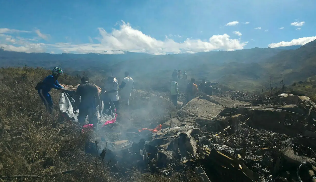 Petugas dibantu relawan memeriksa kondisi pesawat Hercules TNI AU yang jatuh di kawasan Wamena, Papua, Minggu (18/12). Pesawat yang dipiloti Mayor (Pnb) Marlon Kawer itu dilaporkan jatuh dengan muatan 12 ton logistik. (HANDOUT/SEARCH AND RESCUE TEAM/AFP)