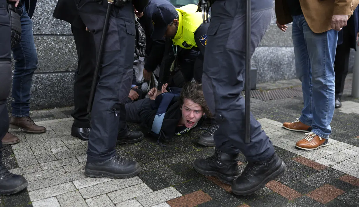 Polisi menahan seorang pengunjuk rasa setelah dia berlari, berteriak, ke arah Emmanuel Macron ketika presiden Prancis itu tiba di kampus sains Universitas Amsterdam pada hari kedua kunjungan kenegaraannya ke Belanda. (AP Photo/Peter Dejong)