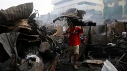 Seorang warga mengangkat puing-puing bangunan usai kebakaran kota Quezon, Metro Manila di Filipina (28/12). Dalam kejadian ini sejumlah warga mengalami luka-luka dan tidak ada korban jiwa. (REUTERS/Erik De Castro)