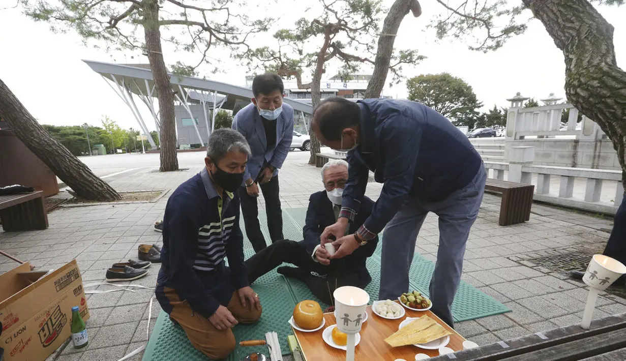 Pengungsi Korea Utara Jo Kyeong-hyeon (kedua dari kanan) dan anggota keluarganya menawarkan anggur untuk menghormati leluhur mereka di Korea Utara saat merayakan Chuseok dekat perbatasan dengan Korea Utara di Paviliun Imjingak, Paju, Selatan Korea, Kamis (1/10/2020). (AP Photo/Ahn Young-joon)