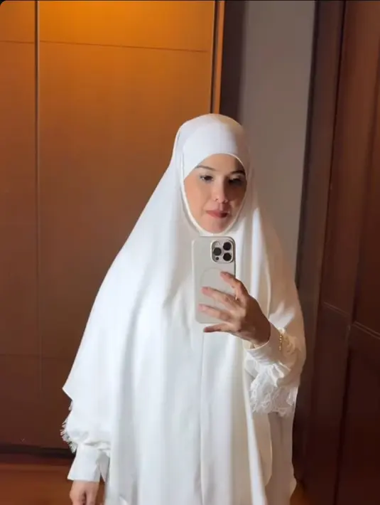 Gaya hijab yang dikenakan Annisa Pohan dalam foto ini adalah model mukena berwarna putih polos dengan desain sederhana namun elegan. Mukena ini memiliki potongan yang longgar dan nyaman, dengan aksen renda di bagian bawah yang menambah kesan anggun. (Liputan6.com/IG/@annisayudhoyono)