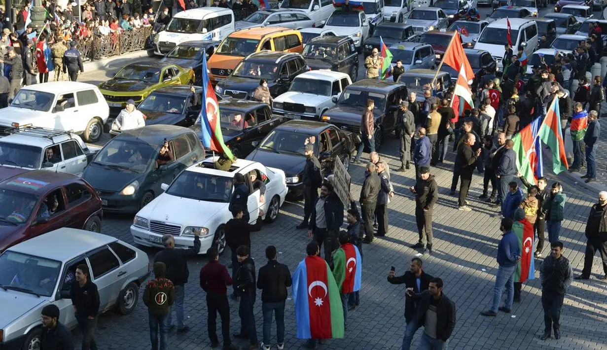 Rakyat Azerbaijan mengibarkan bendera nasional di Ganja, Azerbaijan, Selasa (10/11/2020). Armenia dan Azerbaijan mengumumkan perjanjian damai untuk menghentikan pertempuran atas wilayah Nagorno-Karabakh di Azerbaijan berdasarkan pakta yang ditandatangani dengan Rusia. (AP Photo/Aydin Mammedov)