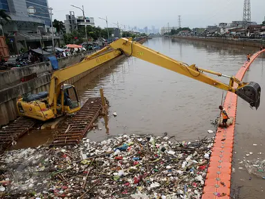 Petugas kebersihkan dibantu alat berat membersihkan sampah di Sungai Kanal Banjir Barat, Jakarta, Senin (14/11). Hujan yang terjadi di hulu Banjir Kanal Barat mengakibatkan meningkatnya debit air yang disertai sampah. (Liputan6.com/Johan Tallo)