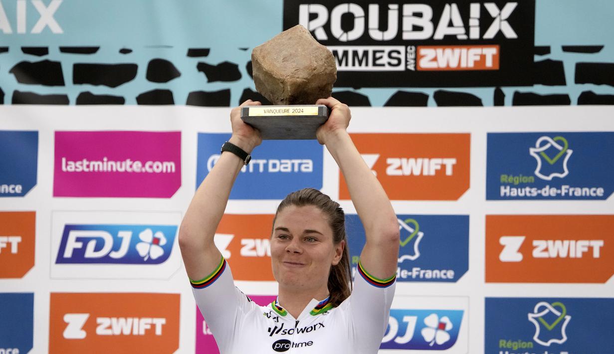 Pembalap Team SD Worx - Protime, Lotte Kopecky mengangkat trofi setelah memenangkan perlombaan balap sepeda Paris Roubaix Femmes 2024 yang menempuh 148,5km antara Denain hingga Roubaix, Prancis, Sabtu (06/07/2024) waktu setempat. (AFP/Christophe Ena)