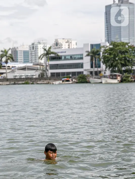 Seorang anak berenang di Danau Sunter, Jakarta, Selasa (2/2/2021). Minimnya lahan bermain anak membuat mereka memanfaatkan tempat yang tidak semestinya untuk bermain karena adanya risiko hanyut dan tenggelam bila tidak mampu untuk berenang. (Liputan6.com/Faizal Fanani)