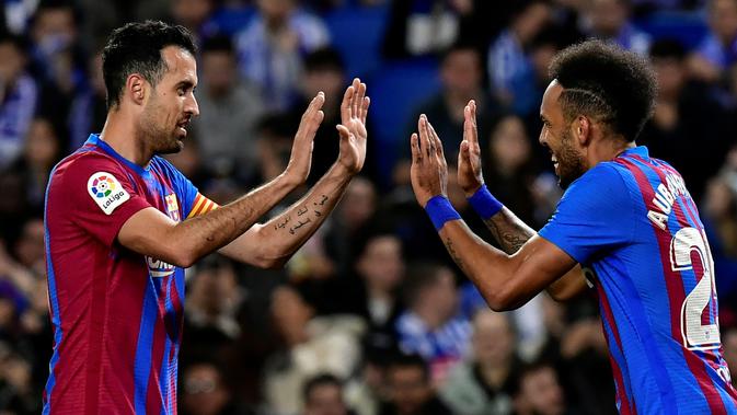 <p>Sergio Busquets dan Pierre-Emerick Aubameyang merayakan gol ke gawang Real Sociedad pada laga lanjutan Liga Spanyol 2021/2022 di Reale Arena, Jumat (22/4/2022). (AP/Alvaro Barrientos)</p>