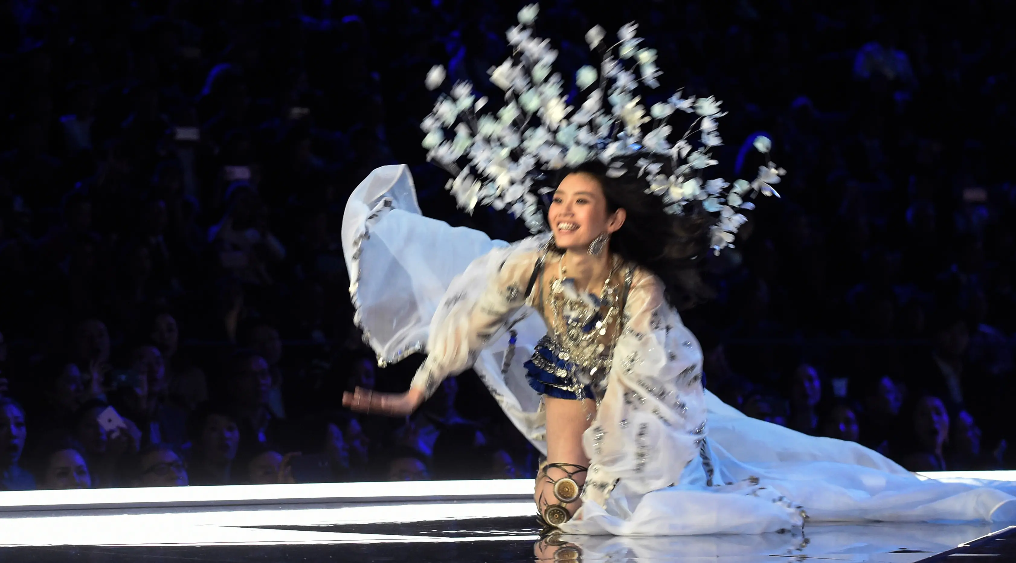 Model Tiongkok, Ming Xi jatuh tersungkur di atas catwalk Victoria’s Secret Fashion Show 2017 saat memperagakan koleksi lingerie di Shanghai, Senin (20/11). Ming mengenakan busana warna biru dan silver dengan headpiece bunga yang rumit. (FRED DUFOUR/AFP)