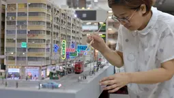 Pembuat model Maggie Chan dari Toma Miniatures bekerja di studionya di Hong Kong, 23 Juni 2021. Dua pembuat model Hong Kong mencoba melestarikan masa lalu arsitektur kota dalam bentuk miniatur yang sangat detail. (Peter PARKS/AFP)
