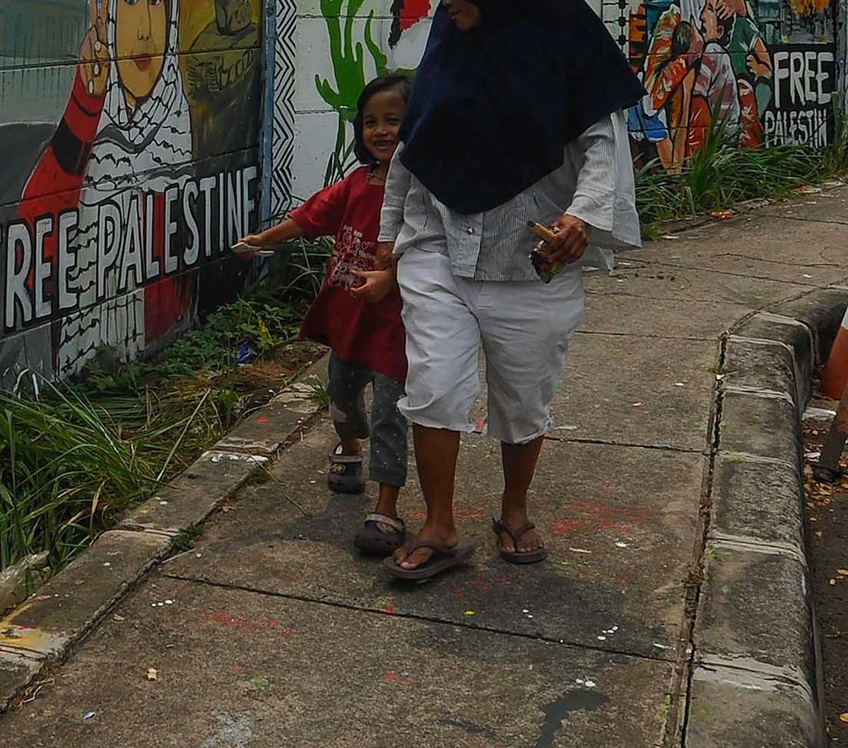 Warga&nbsp;melintas di depan mural dukungan untuk Palestina di Jalan Juanda, Kota Depok, Jawa Barat, pada Rabu (8/11/2023).&nbsp;Merdeka.com/Arie Basuki
