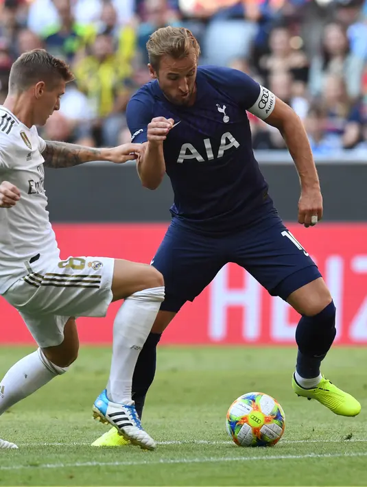 Gelandang Real Madrid, Toni Kroos berusaha merebut bola dari striker Tottenham Hotspur, Harry Kane selama pertandingan Audi Cup 2019 di stadion Allianz Arena di Munich, Jerman (30/7/2019). Tottenham akan melawan Bayern Munchen di babak final. (AFP Photo/Christof Stache)