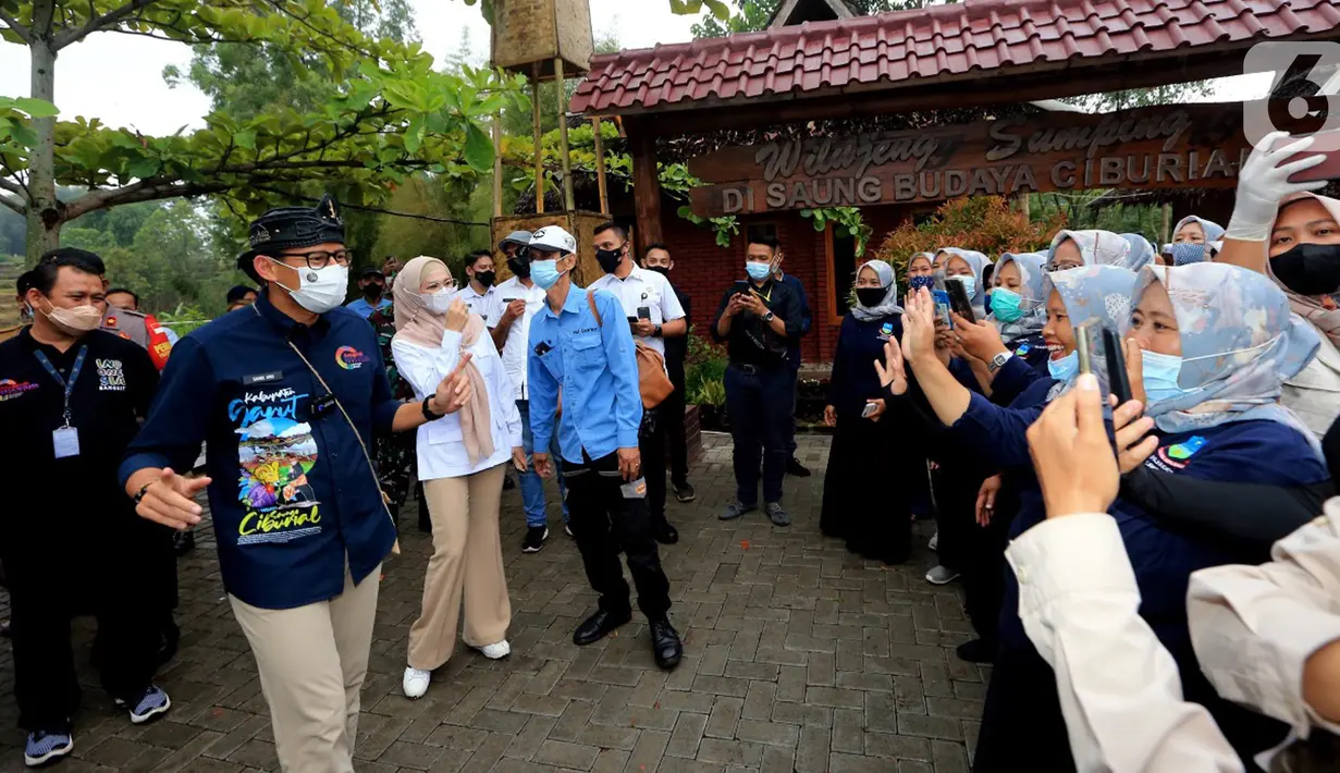 Menteri Pariwisata dan Ekonomi Kreatif Sandiaga Uno (kiri) menyapa warga pada kunjungannya di Desa Wisata Saung Ciburial, Kecamatan Samarang, Garut, Jawa Barat, Senin (18/10/2021). Hujan deras tidak menyurutkan warga untuk menyambut kunjungan kerja Sandiaga Uno. (Liputan6.com/HO/Parekraf)